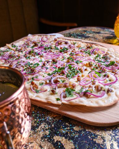 Unser Classic Flammkuchen mit Tiroler Tiroler Bio-Speck, Zwiebeln und Petersil.